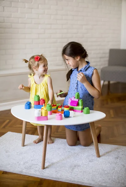 Δύο Χαριτωμένα Κοριτσάκια Παίζουν Τουβλάκια Στο Τραπέζι — Φωτογραφία Αρχείου