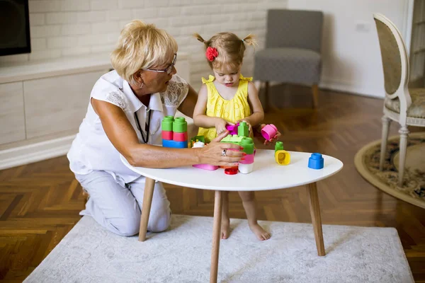 Γιαγιά Και Χαριτωμένο Κοριτσάκι Παίζει Πλαστικά Μπλοκ Στο Δωμάτιο — Φωτογραφία Αρχείου
