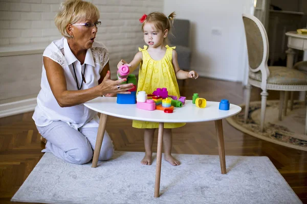 Γιαγιά Και Χαριτωμένο Κοριτσάκι Παίζει Πλαστικά Μπλοκ Στο Δωμάτιο — Φωτογραφία Αρχείου