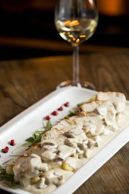 Krem mantar soslu rendelenmiş gnocchi soslu tavuk eti ve masada beyaz şaraplı füme peynir.