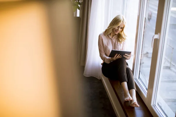 Schöne Junge Kaukasische Blondine Sitzt Fenster Wohnzimmer Und Nutzt Ein — Stockfoto