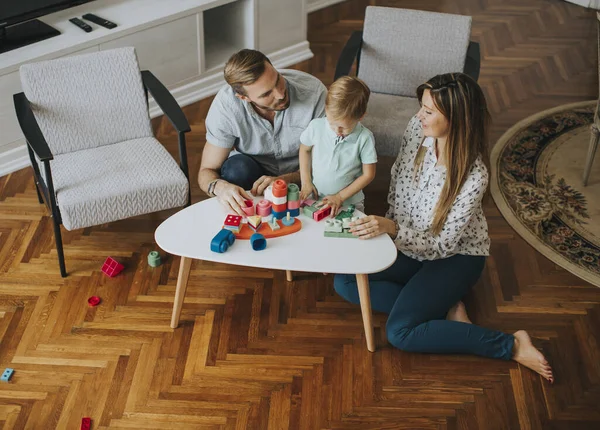 可愛いです男の子遊びますおもちゃでザリビングルームとともにお父さんとお母さん — ストック写真