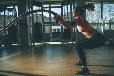 Spor salonunda halat egzersizi yapan genç ve güzel bir kadın.