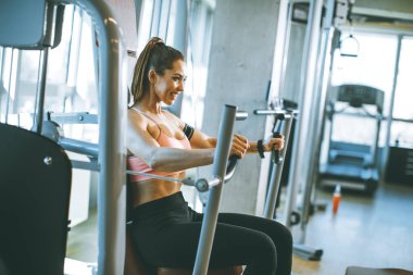 Modern spor salonundaki göğüs presi makinesinde egzersiz yapan kararlı genç bir kadın.