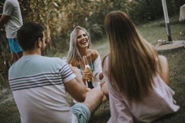 Bir grup mutlu genç arkadaş göl kenarındaki doğanın tadını çıkarıyorlar.