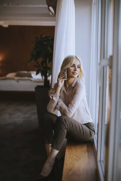 Jolie Jeune Femme Blonde Avec Téléphone Portable Assis Près Fenêtre — Photo