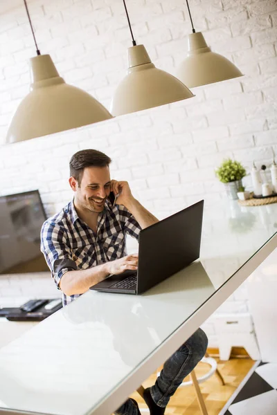 Knappe Jongeman Die Thuis Het Keukenbureau Zit Laptop Mobiele Telefoon — Stockfoto