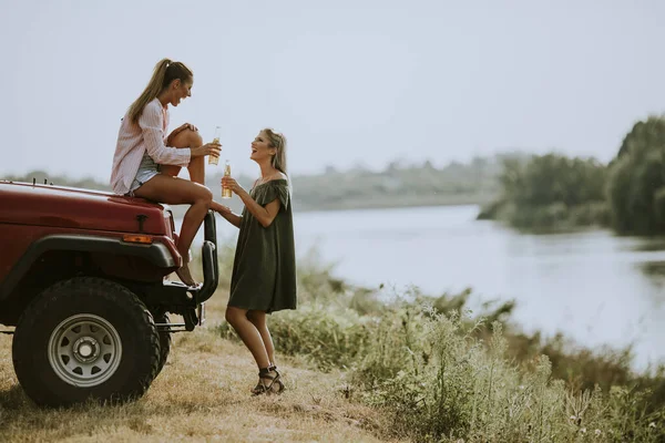 Две Счастливые Девушки Пьют Сидр Машины Берегу Озера — стоковое фото