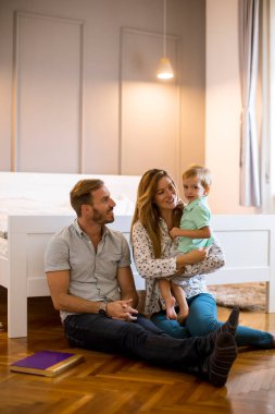Mutlu genç aile yatak odasında yerde oynuyor.