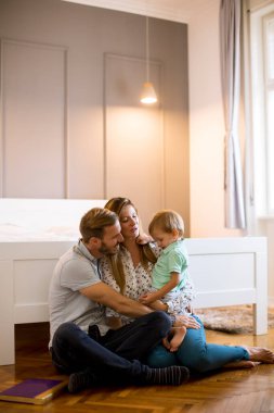 Mutlu genç aile yatak odasında yerde oynuyor.