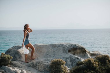 Deniz kenarında kayalarda yürüyen bikinili güzel bir kadın.