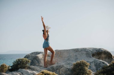 Deniz kenarında kayalarda yürüyen bikinili güzel bir kadın.