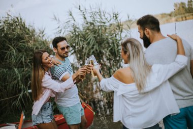 Bir grup mutlu genç arkadaş göl kenarındaki doğanın tadını çıkarıyorlar.