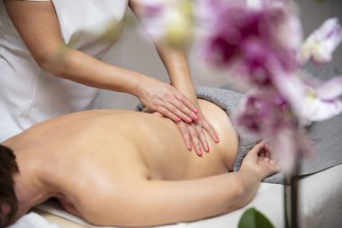 Kaplıcada sırt masajı yaparken dinlenen genç bir kadın.