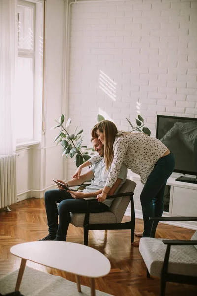 快乐的年轻夫妇在客厅里看着数码平板电脑 — 图库照片