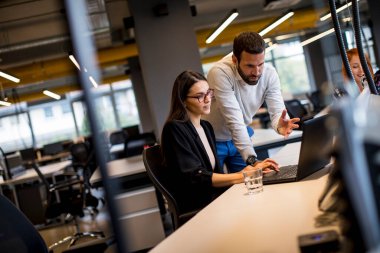 Bir grup genç iş adamı dizüstü bilgisayarda birlikte çalışıyorlar.