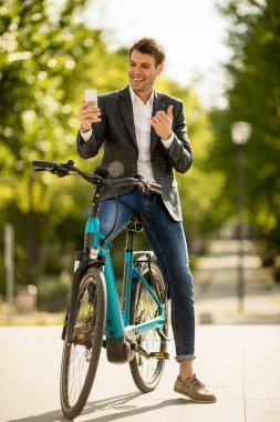 Bisikletli genç işadamı cep telefonuyla selfie çekiyor.