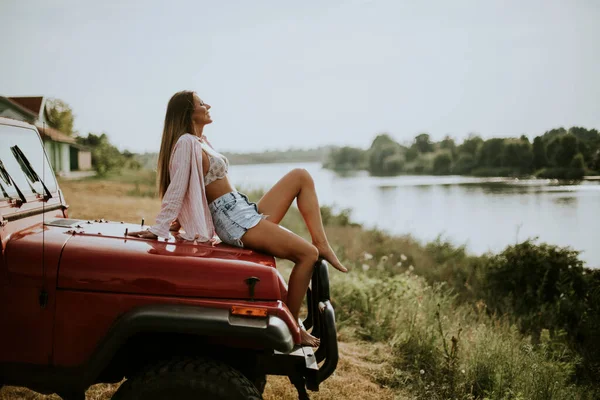 Όμορφη Νεαρή Γυναίκα Κάθεται Μια Κόκκινη Κουκούλα Αυτοκινήτου Και Απολαμβάνει — Φωτογραφία Αρχείου