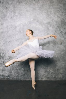 Yaşlı taşra duvarına karşı klasik bale yapan genç bir balerin.