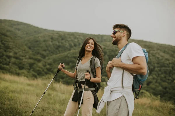 Sorrindo Jovem Casal Andando Com Mochilas Sobre Colinas Verdes — Fotografia de Stock