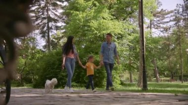 Güzel, mutlu bir aile parkta bizon köpeğiyle yürüyor.