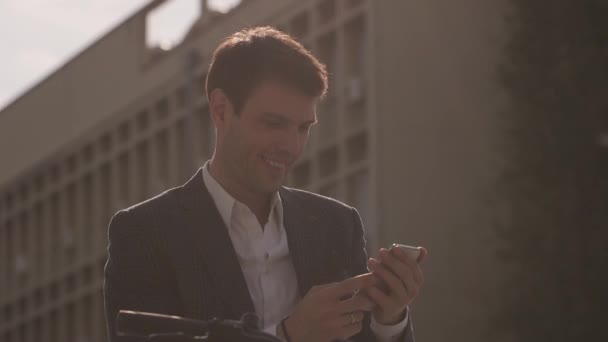 Bonito jovem empresário na ebike usando telefone celular — Vídeo de Stock