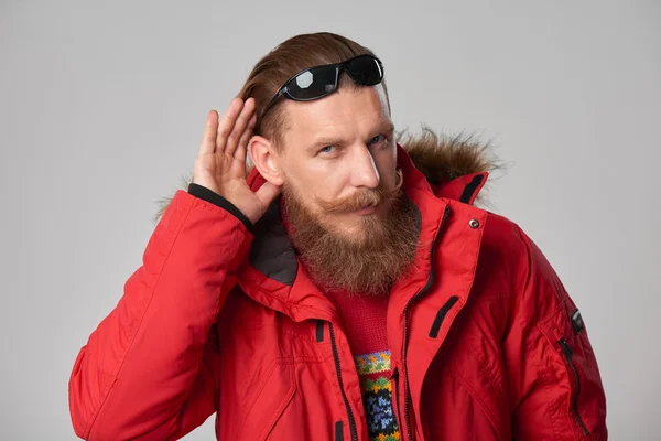 Hombre vistiendo chaqueta de invierno roja con la mano en la oreja — Foto de Stock