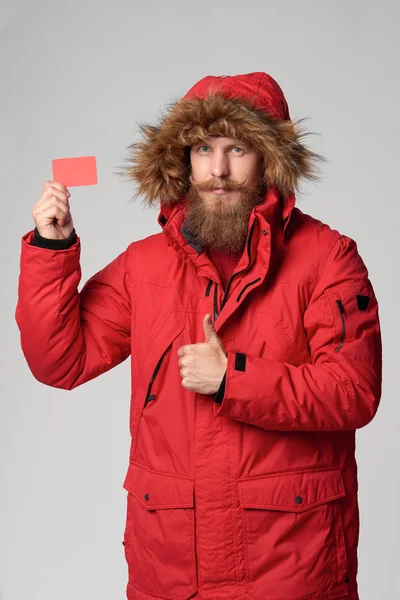Человек в зимней куртке держит кредитку — стоковое фото