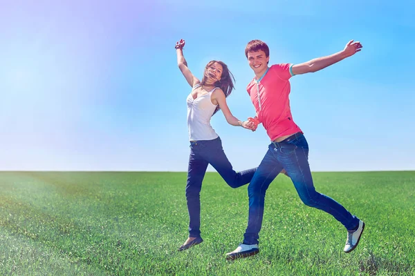 Pasangan bahagia melompat di lapangan hijau — Stok Foto