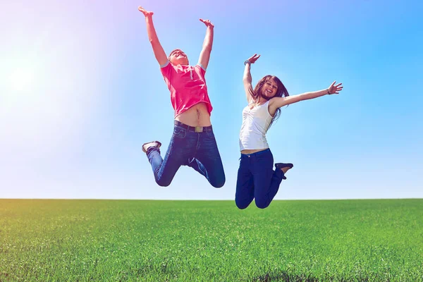 Happy couple jumping in green field — Stock Photo, Image