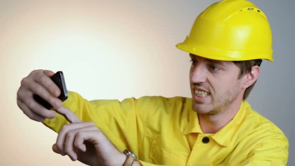 Constructor hombre en casco usando mensajes de texto en el teléfono móvil — Vídeo de stock