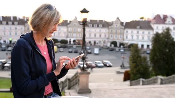 Vrouw zitten buiten met behulp van smartphon — Stockvideo