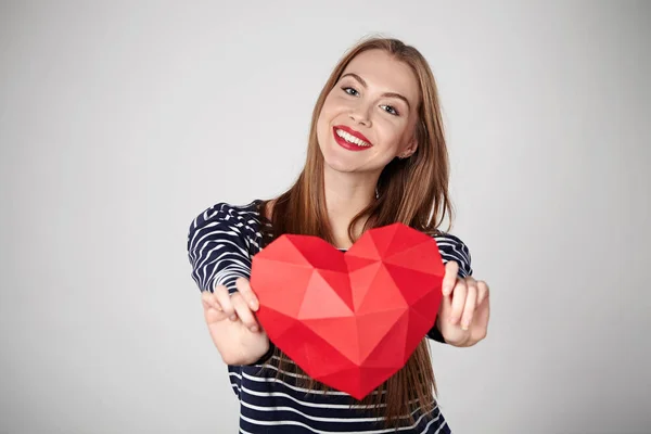 Kırmızı kenarlı kağıt kalp şekli tutan gülümseyen kadın — Stok fotoğraf