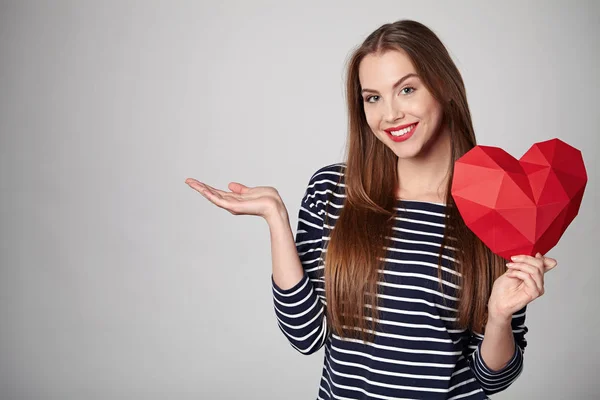 Lachende vrouw met rode veelhoekige papier hart vorm — Stockfoto