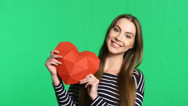 Mujer sonriente sosteniendo papel poligonal rojo en forma de corazón — Vídeos de Stock