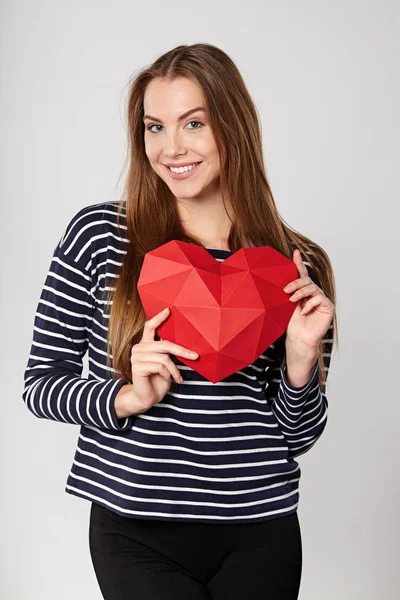 Femme souriante tenant en forme de coeur en papier polygonal rouge — Photo