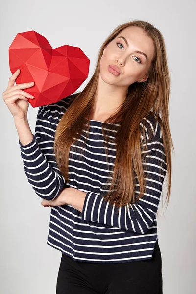 Mujer sonriente sosteniendo papel poligonal rojo en forma de corazón — Foto de Stock