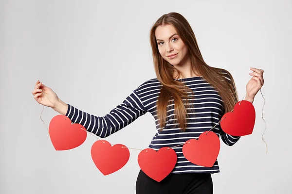 Donna sorridente che tiene ghirlanda di cinque cuori di carta rossa — Foto Stock