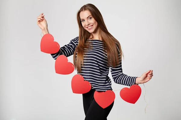 Mujer sonriente sosteniendo guirnalda de cinco corazones de papel rojo —  Fotos de Stock