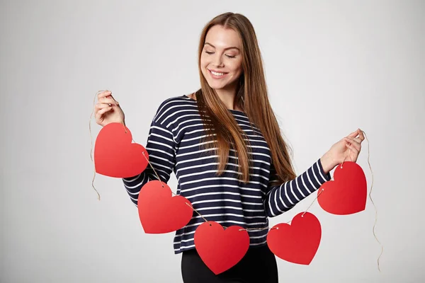 Donna sorridente che tiene ghirlanda di cinque cuori di carta rossa — Foto Stock