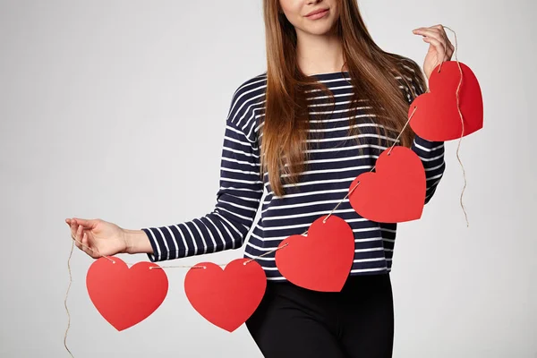 Mujer sonriente sosteniendo guirnalda de cinco corazones de papel rojo —  Fotos de Stock