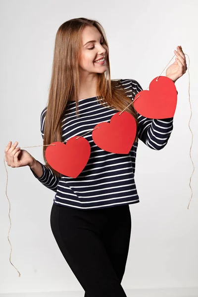 Mujer sonriente sosteniendo guirnalda de tres corazones de papel rojo —  Fotos de Stock