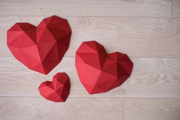 Tre forma di cuore di carta poligonale rossa su bachground di legno — Foto Stock