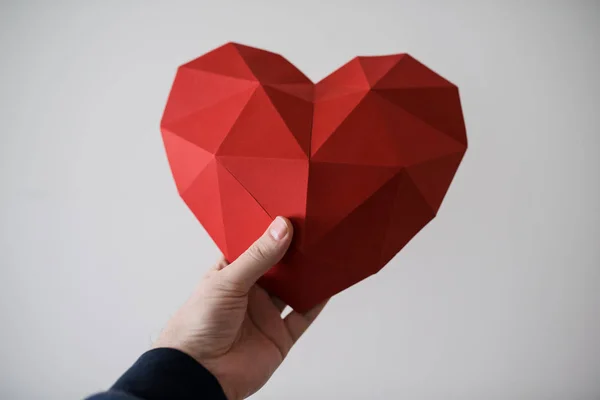 Mano maschile tenendo forma di cuore poligonale rosso — Foto Stock