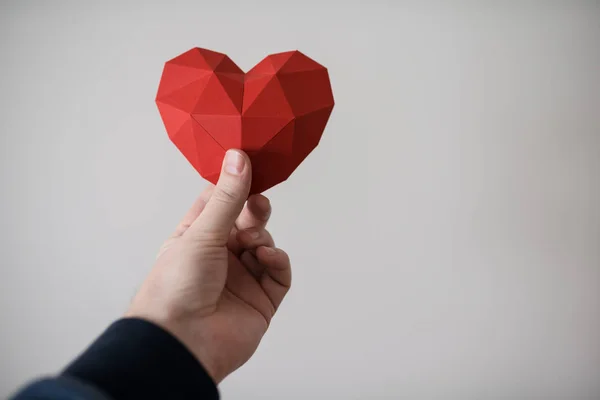Мужская рука с красной многоугольной формой сердца — стоковое фото