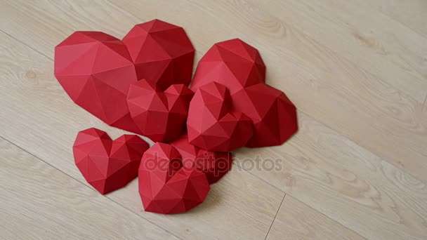 Trois forme de coeur en papier polygonal rouge sur fond de bac en bois — Video