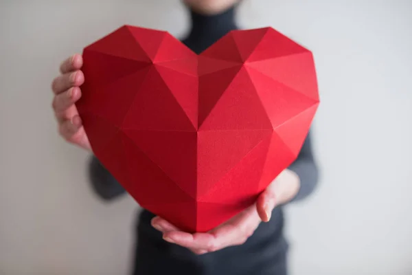 Femme montrant une forme de coeur en papier polygonal rouge — Photo