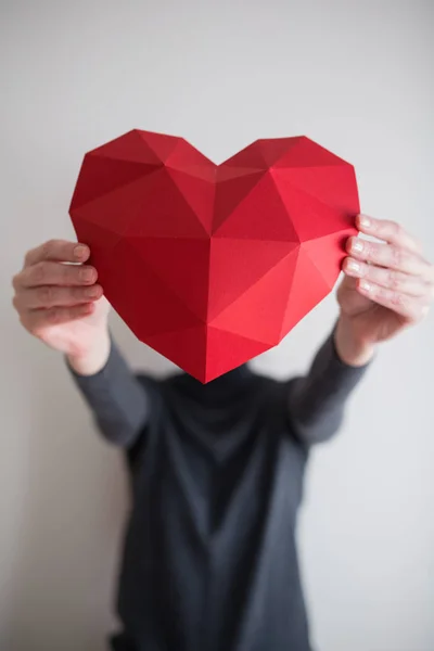 Femme montrant une forme de coeur en papier polygonal rouge — Photo