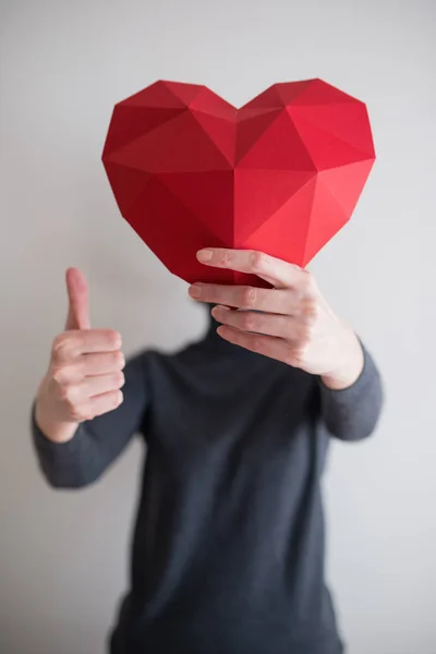 Wanita yang menunjukkan bentuk jantung kertas poligonal merah — Stok Foto