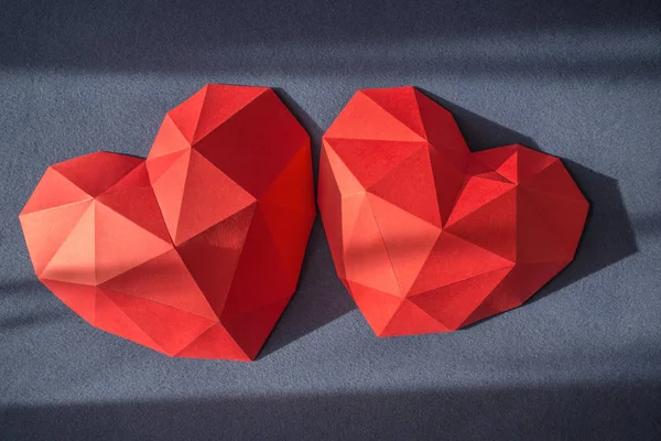 Trois forme de coeur en papier polygonal rouge sur fond de bac en bois — Photo
